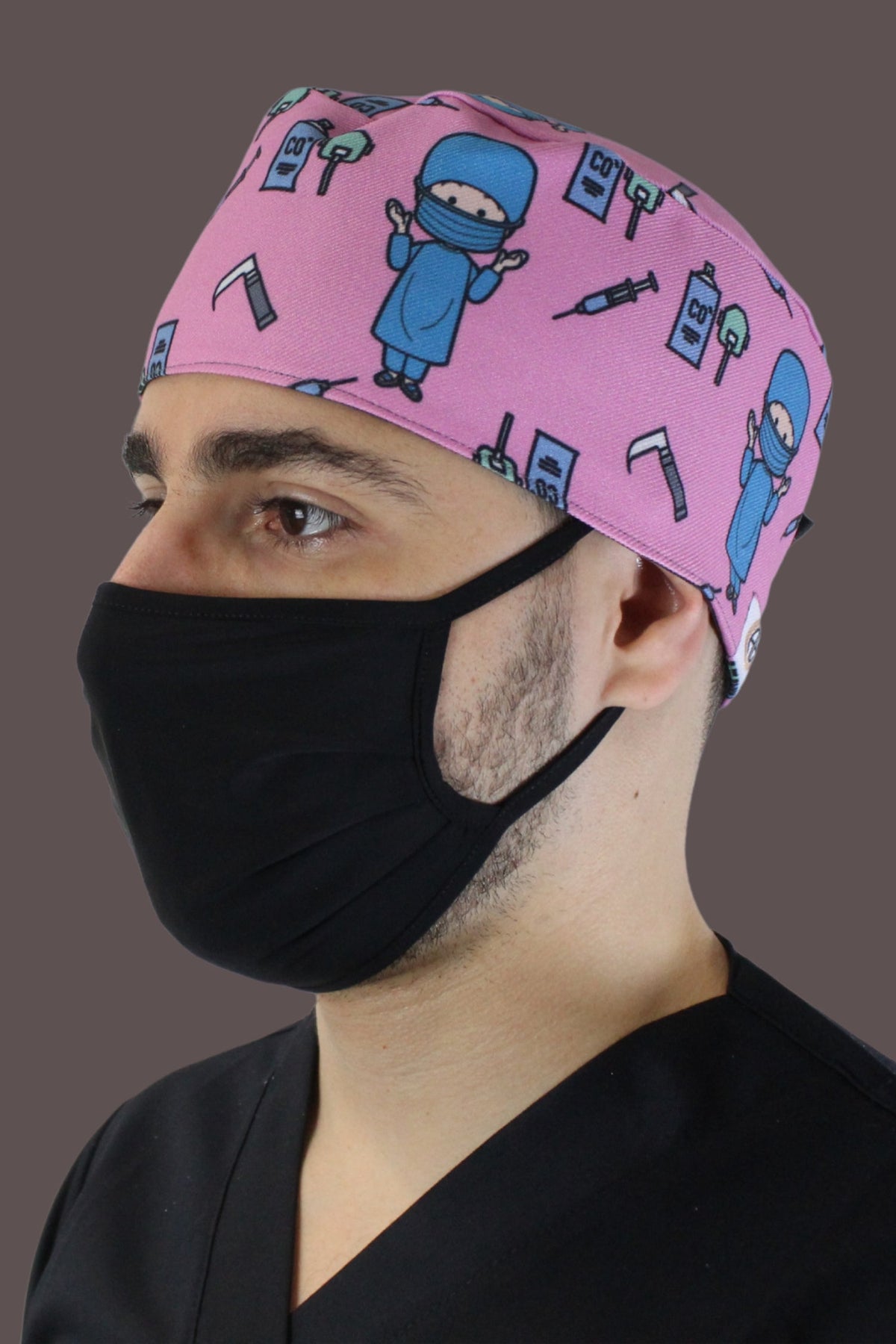Roze medische muts van Aelin met unieke motieven, gedragen door een persoon met een zwart mondmasker